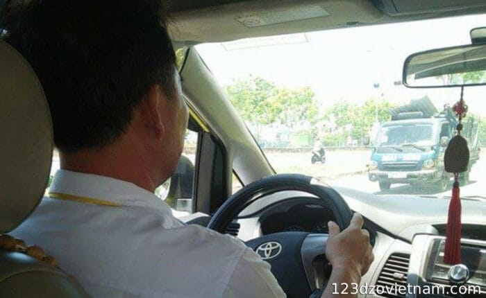 Driver in white uniform driving a taxi in Ho chi Minh city